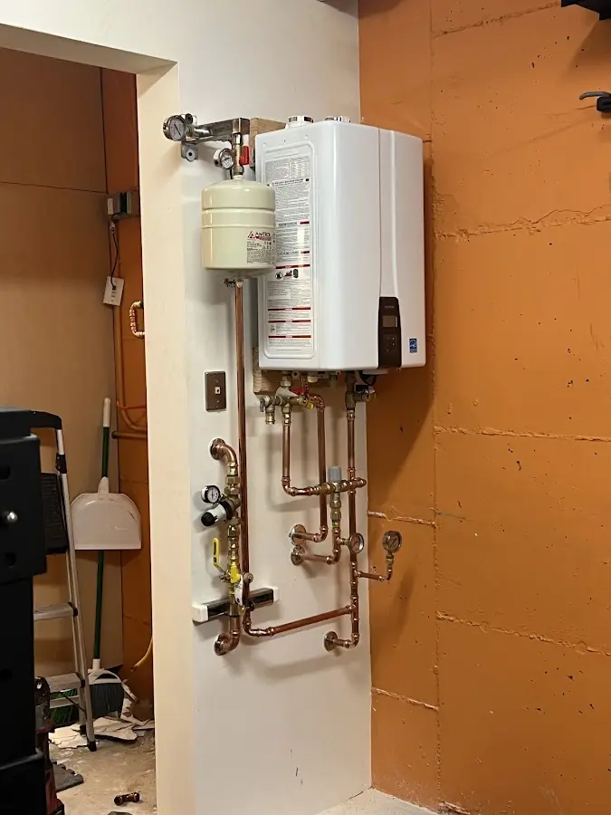 Plumbing technician inspecting water heater connections in Gallup